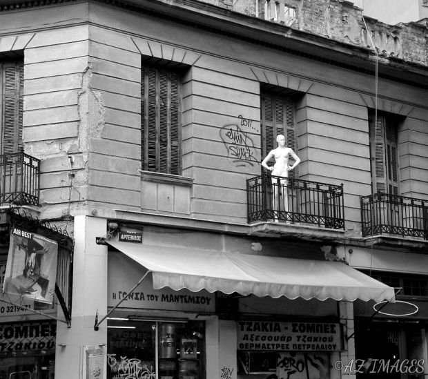A manequin strikes a pose on a balcony.